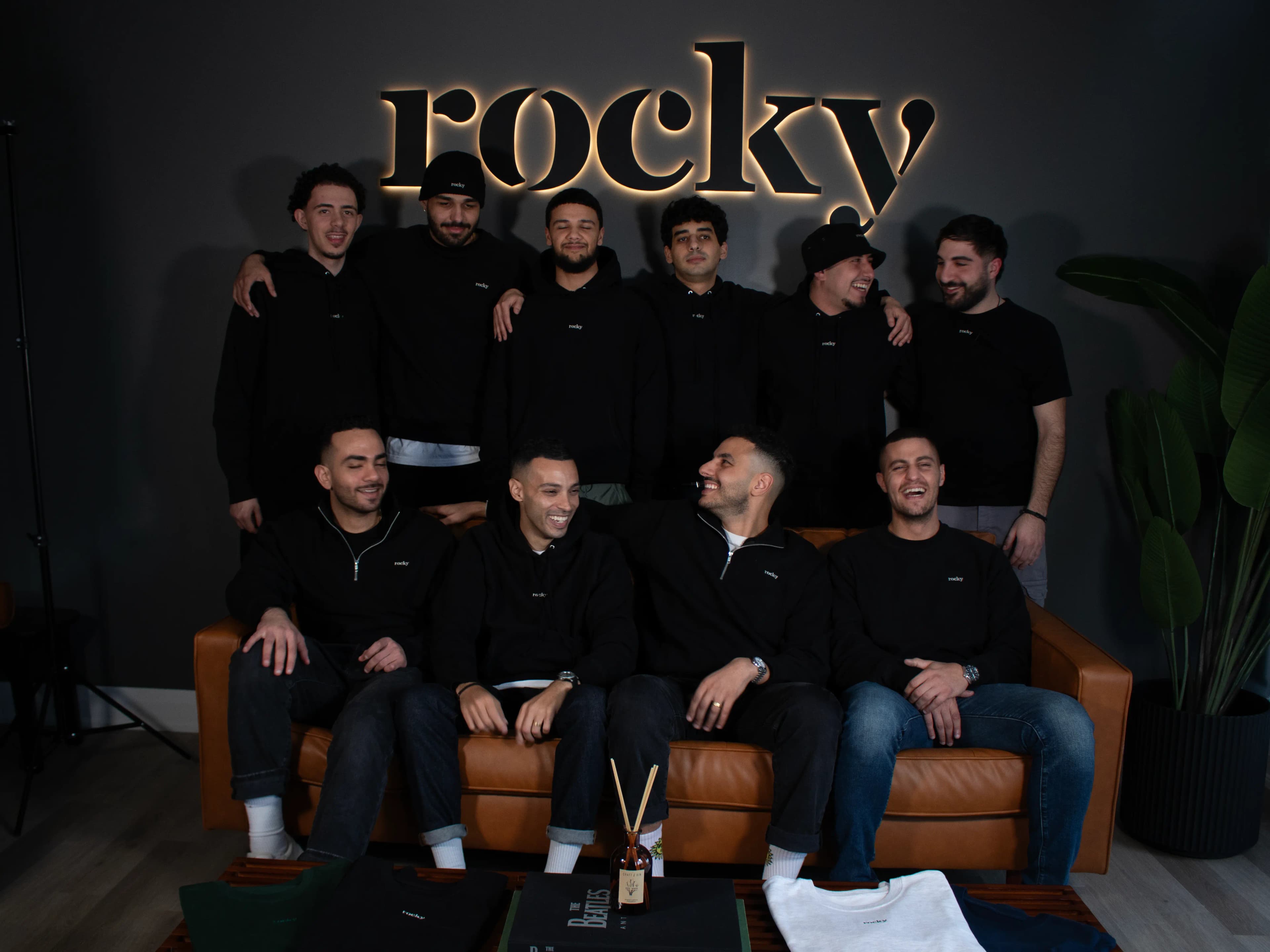 Group of men in black hoodies with illuminated ROCKY sign